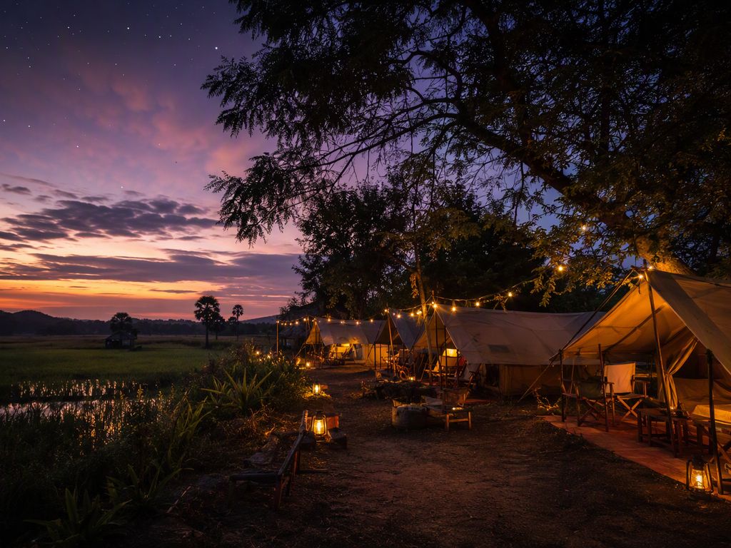 Farm-stay tents with warm lanterns at dusk among fields